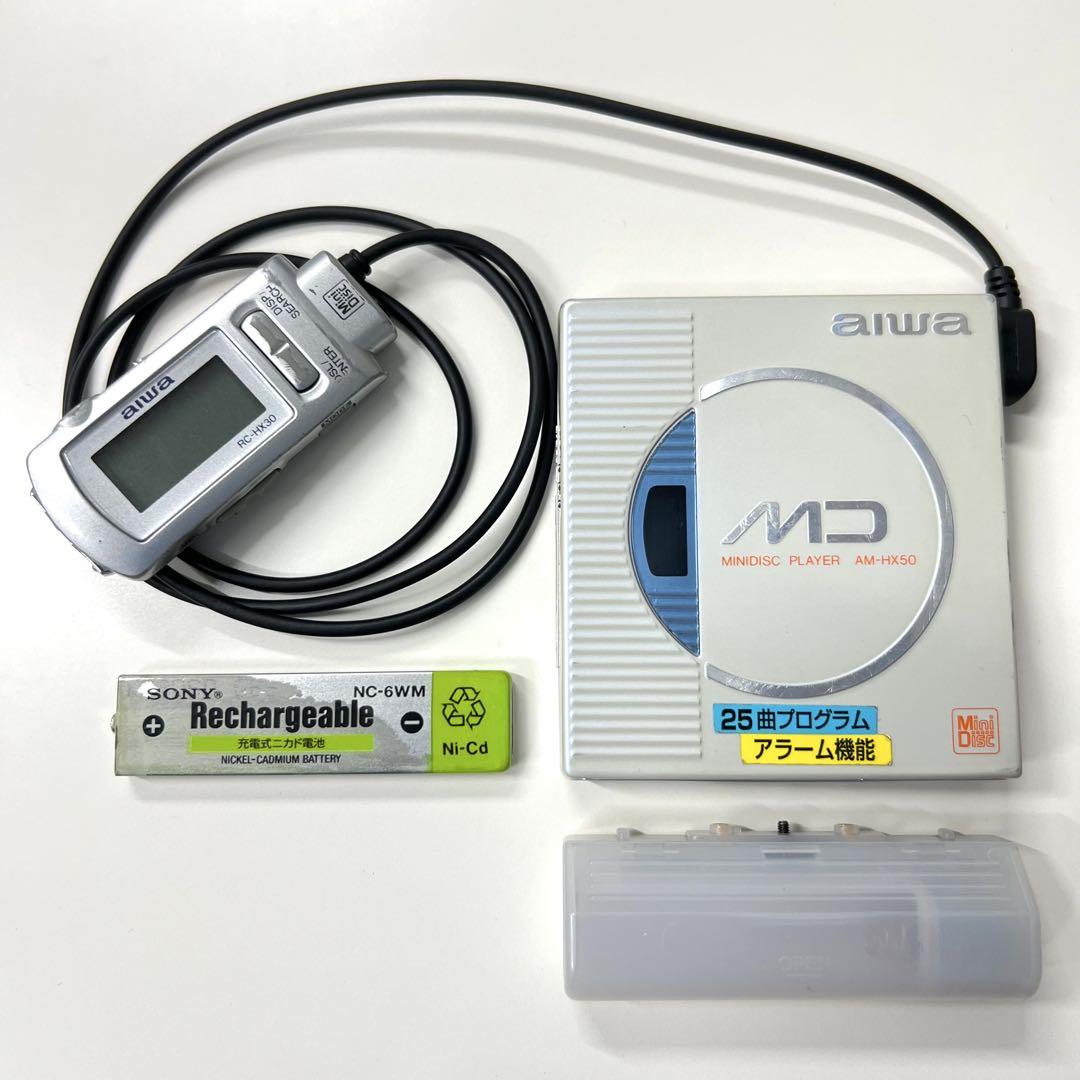 aiwa MD MiniDisc player AM-HX50 with wired remote, a rechargeable battery, and a battery cover on a white background.