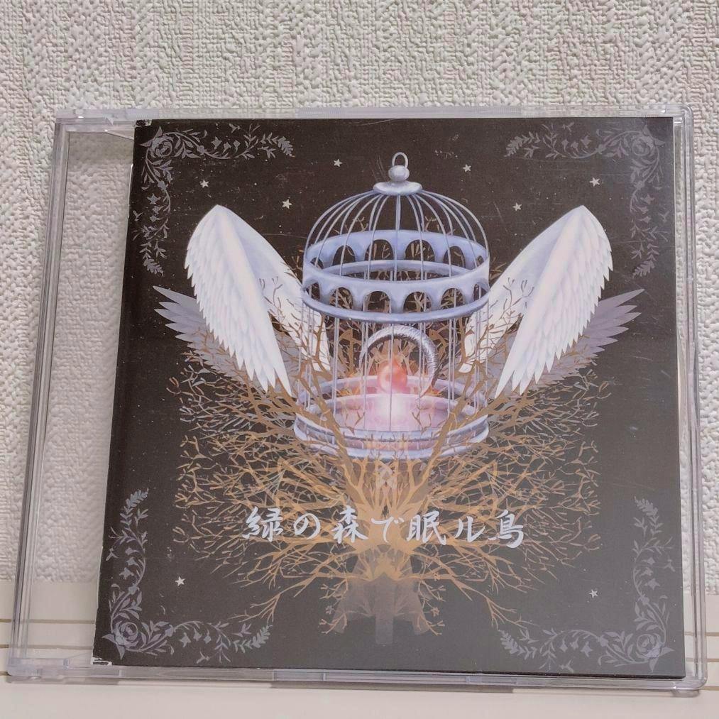 CD front cover artwork showing a birdcage with wings and the Japanese title “緑の森で眠ル鳥”.