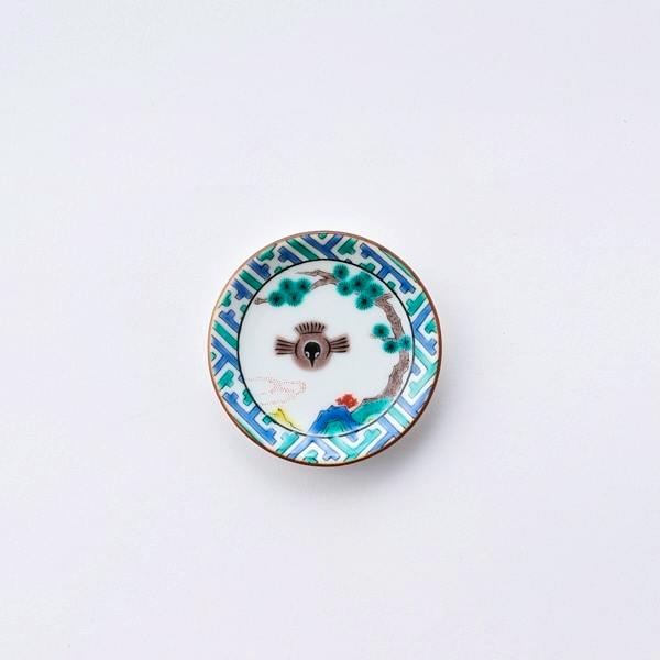 Small round Kutani (九谷焼) ceramic himezara plate showing a decorative bird and tree motif with a turquoise geometric border on a white background.