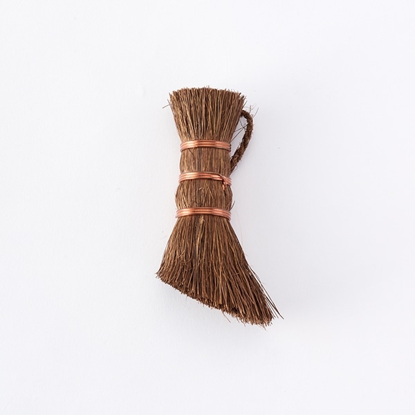 A small palm-fiber kitchen brush bound with three copper-colored bands and a hanging loop on a white background.