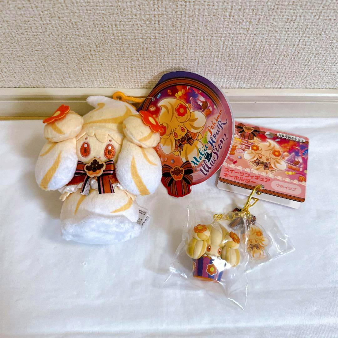 A white and cream マホイップ mascot plush with attached tags and a small matching keychain on a white surface.