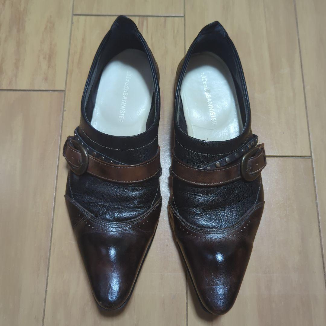 Top-down photo of a pair of Alfred Bannister brown leather slip-on loafers placed side by side on a wooden floor.