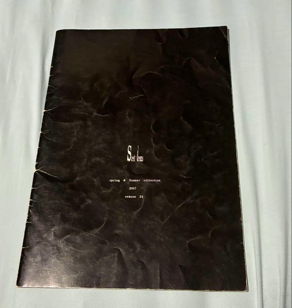 Black-covered alice auaa 2007 SS catalog pamphlet lying on a light-colored fabric.