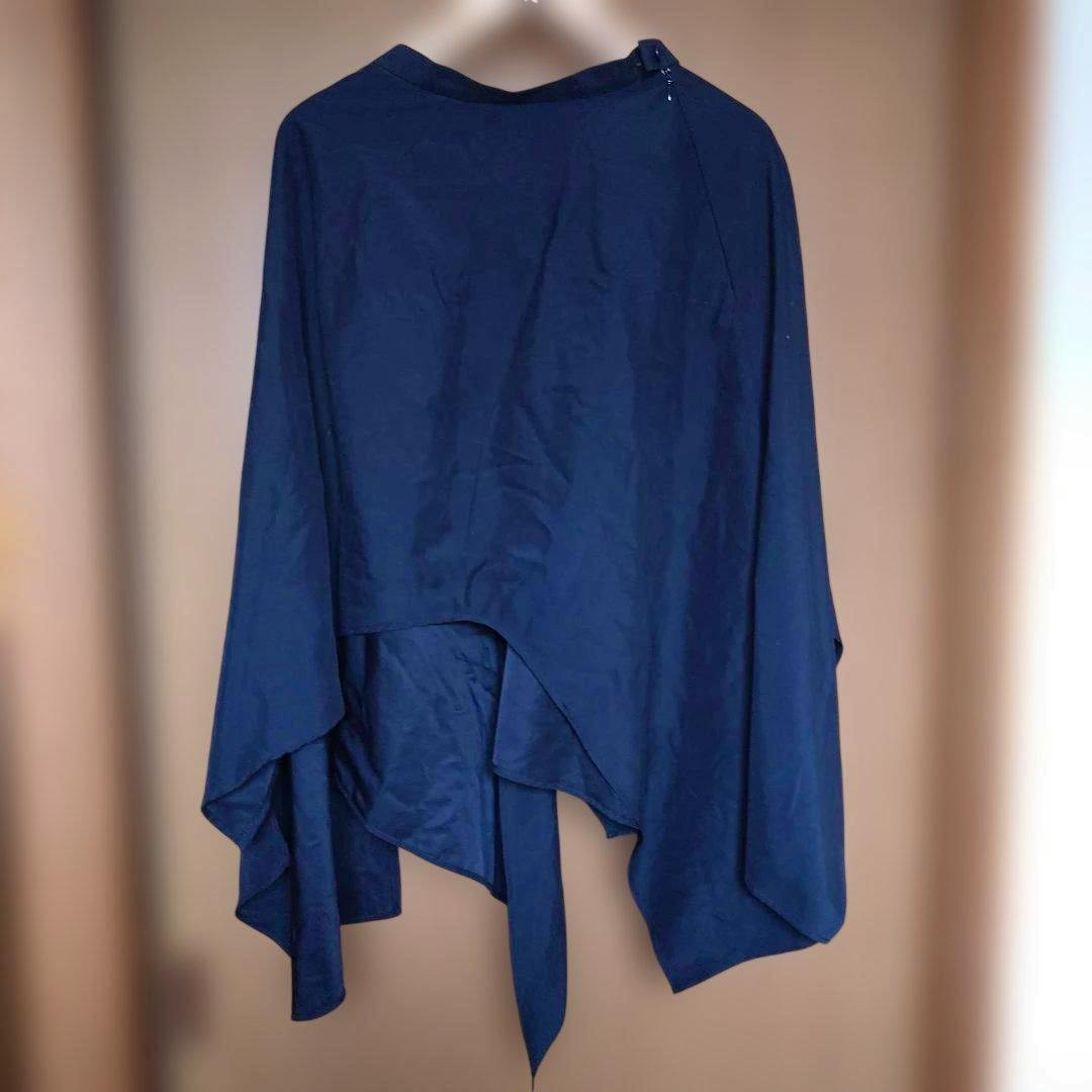 Black asymmetrical long skirt hanging on a hanger showing the draped, uneven hem.