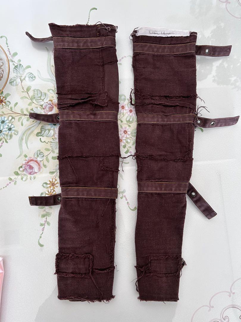 Two maroon arm covers laid flat showing straps, stitching, and frayed edges.