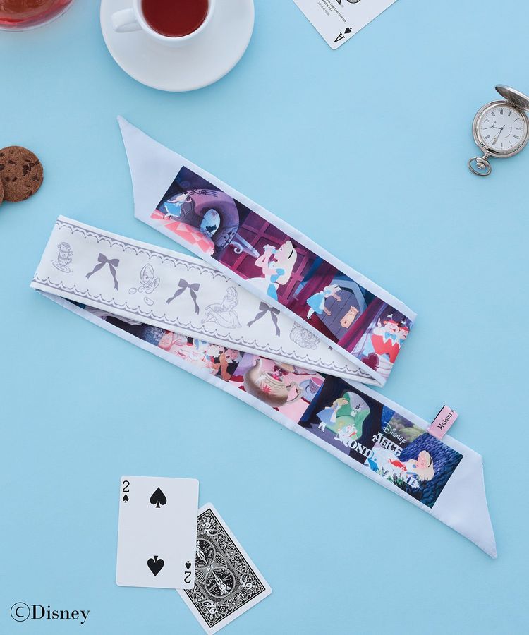 A polyester Alice-themed scarf laid flat with playing cards, a teacup, and a pocket watch on a blue background.