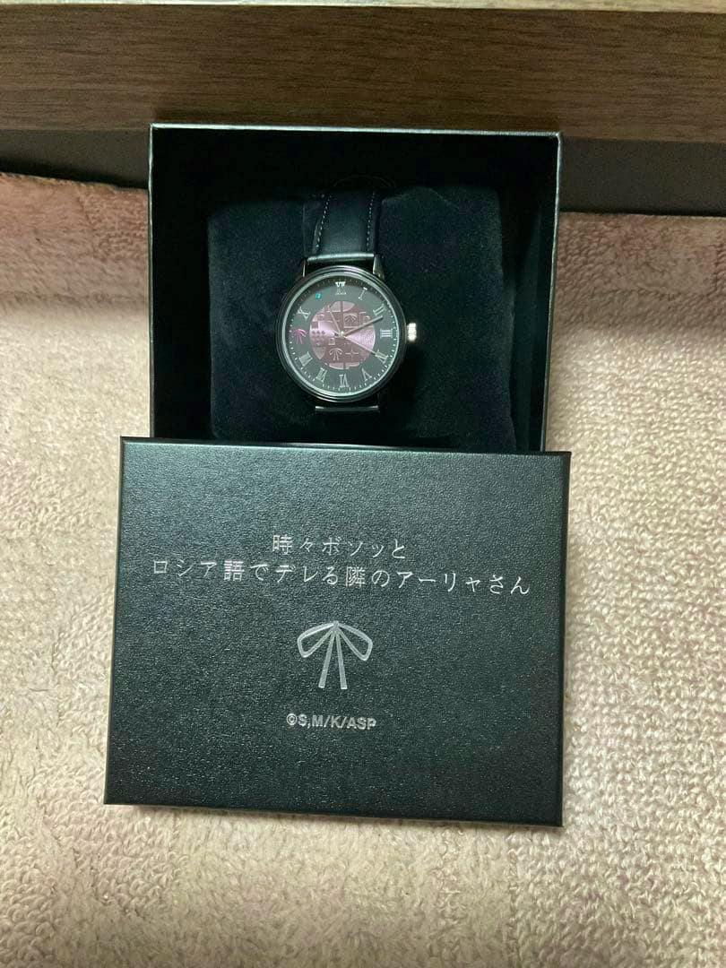 A wristwatch displayed in its presentation box with the box lid showing Japanese text.