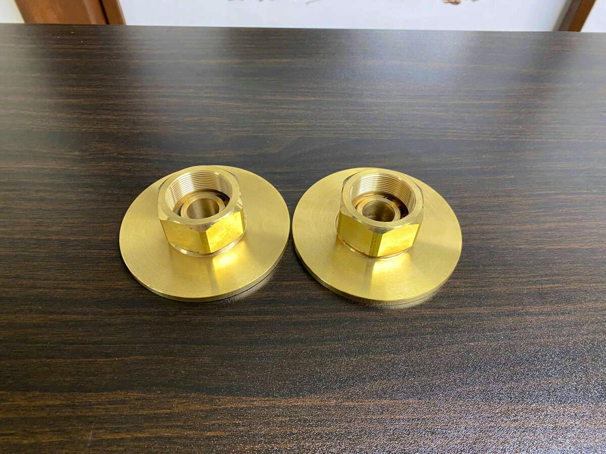 Two brass compression driver throat adapters shown side by side on a dark wood table.