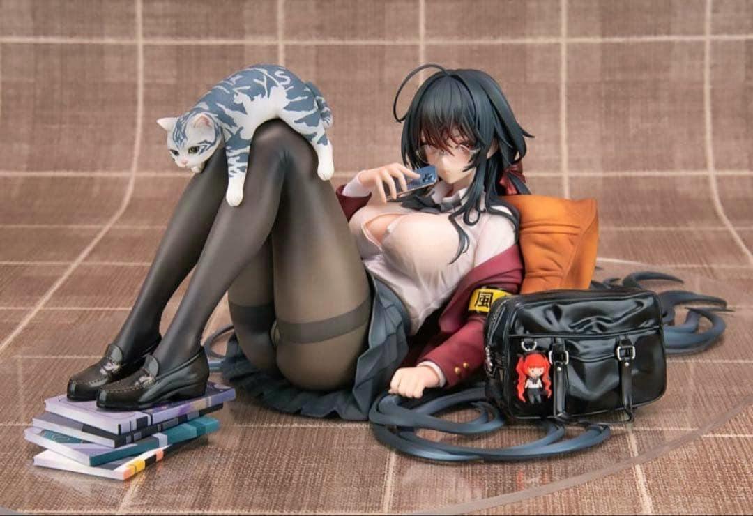 Photo of the 1/7-scale Taihou figure from Azur Lane reclining with a cat on her legs, a school bag, and stacked books.