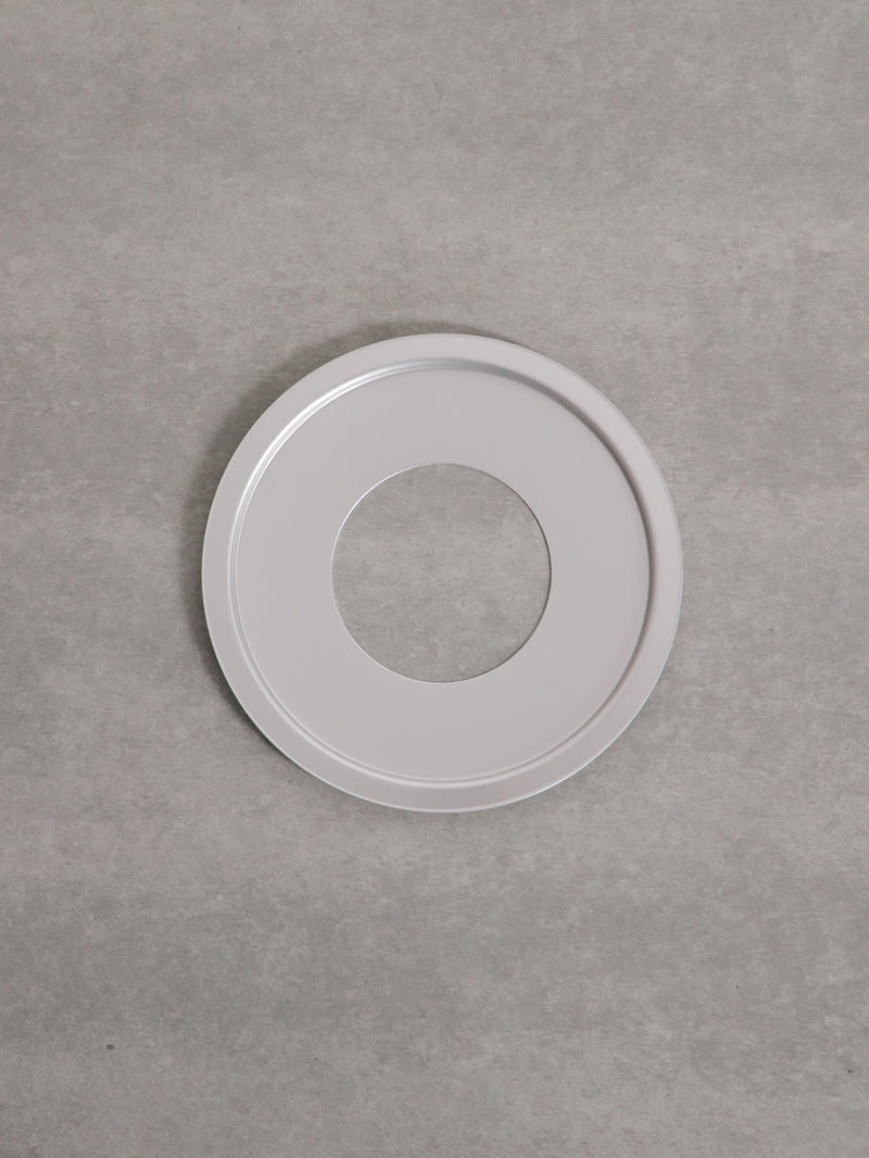 Top-down photo of an aluminum steaming plate (19.5 cm) with a central hole on a gray background.