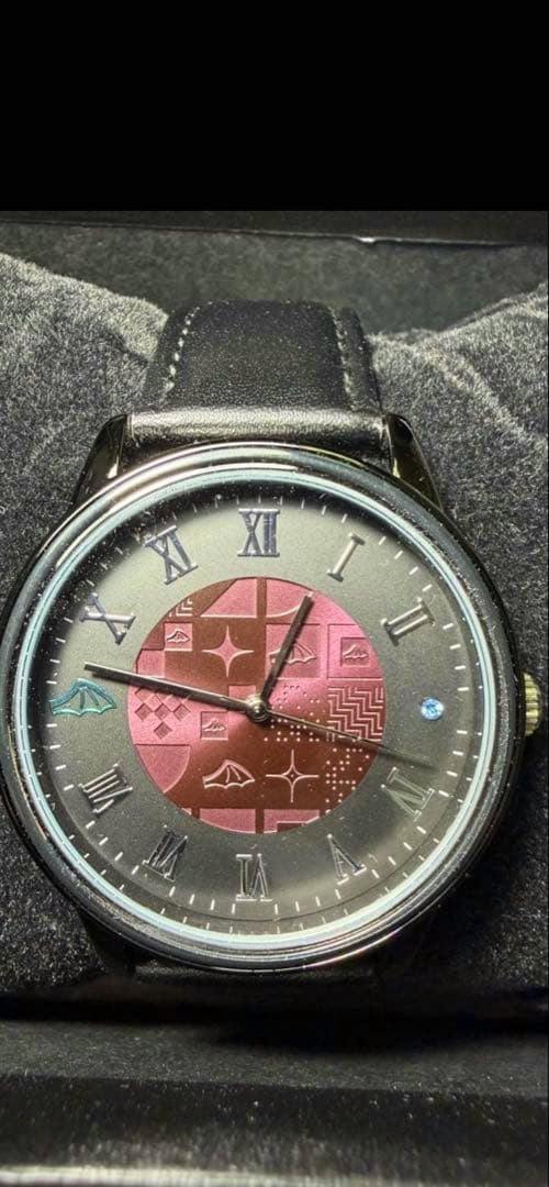 Close-up of the wristwatch face with Roman numerals, a patterned red center, and a black leather strap.