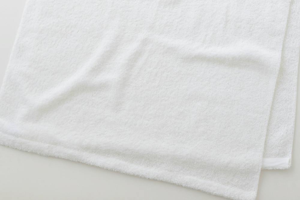 A white cotton bath towel laid flat showing its texture and hem.