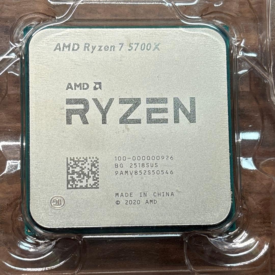 Close-up of an AMD Ryzen 7 5700X CPU top in clear plastic packaging showing the model markings.