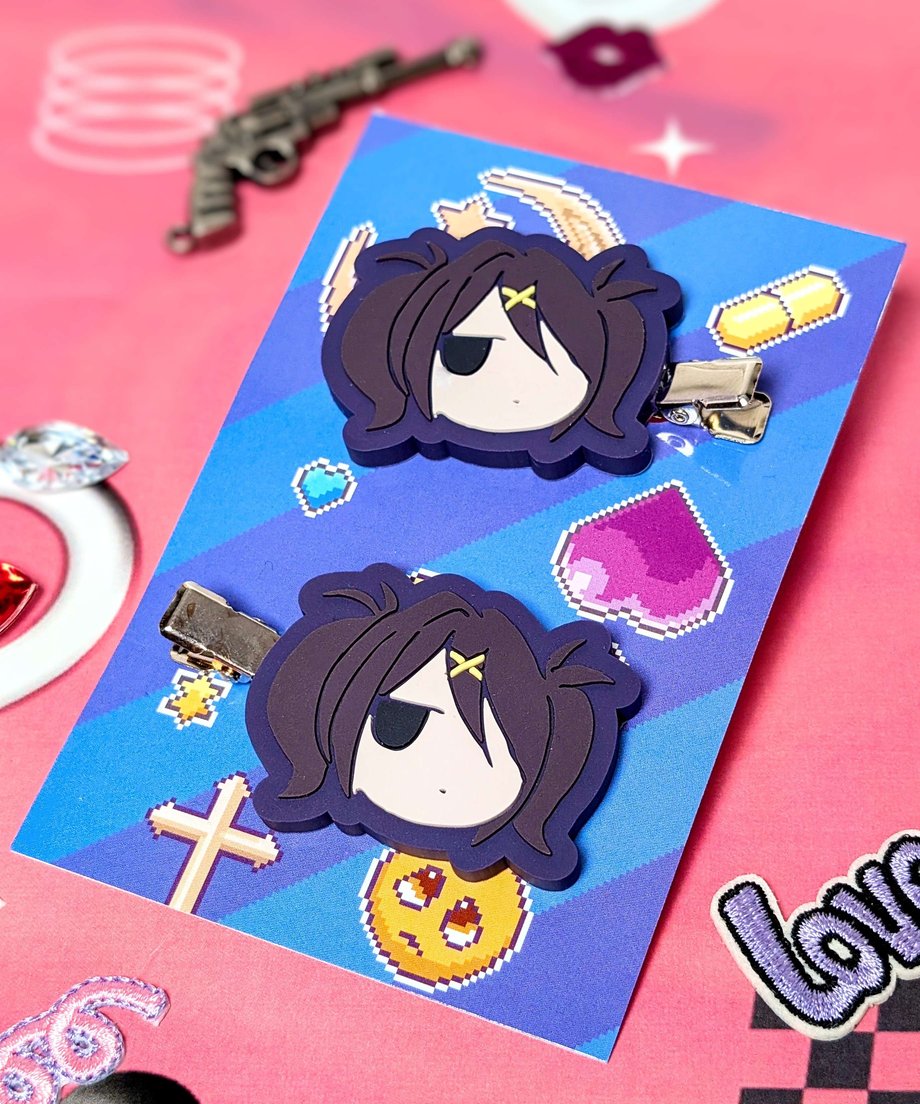 Two character-shaped hair clips on a blue display card against a pink background.