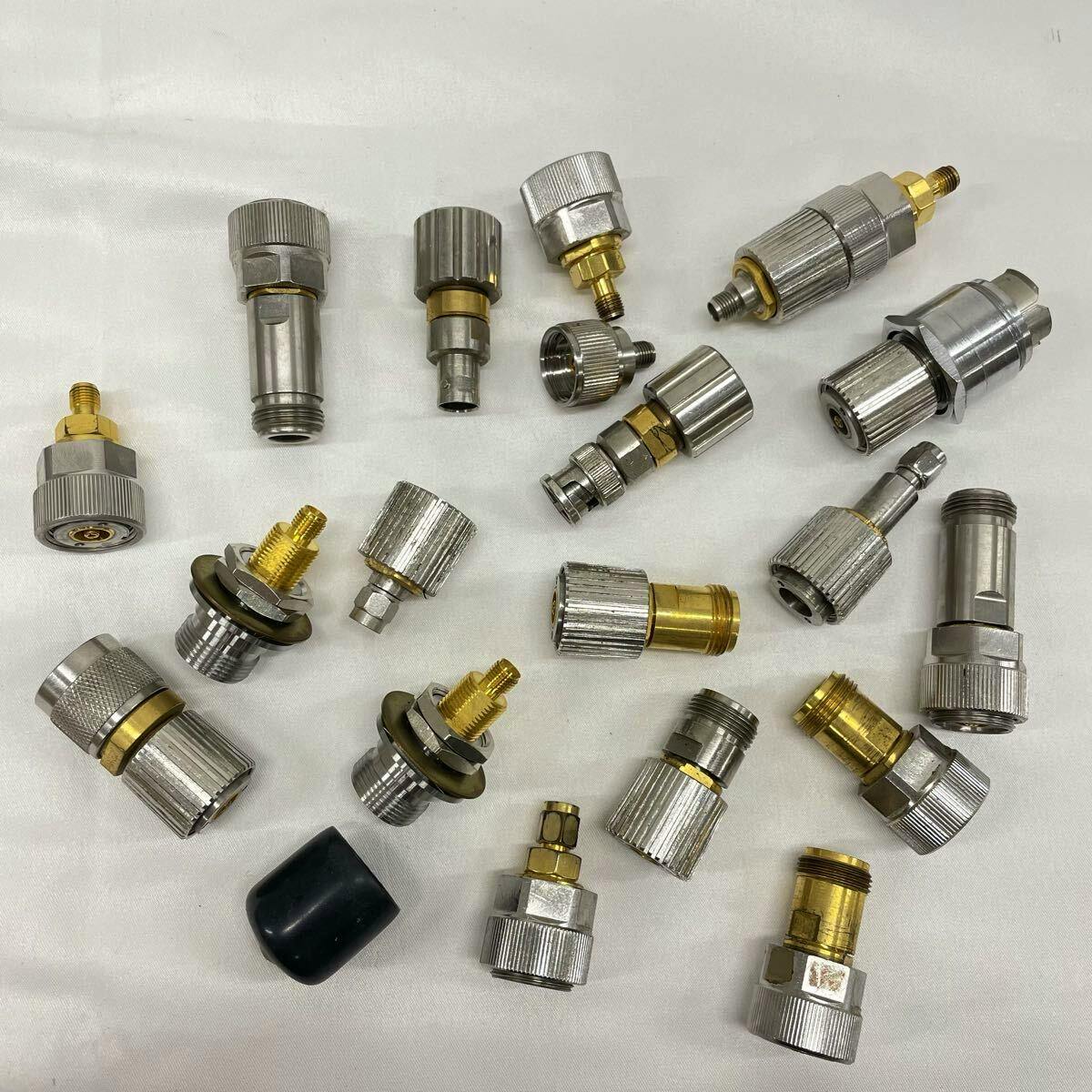 Multiple metal Amphenol APC-7 coaxial conversion adapters and connectors arranged on a white cloth.