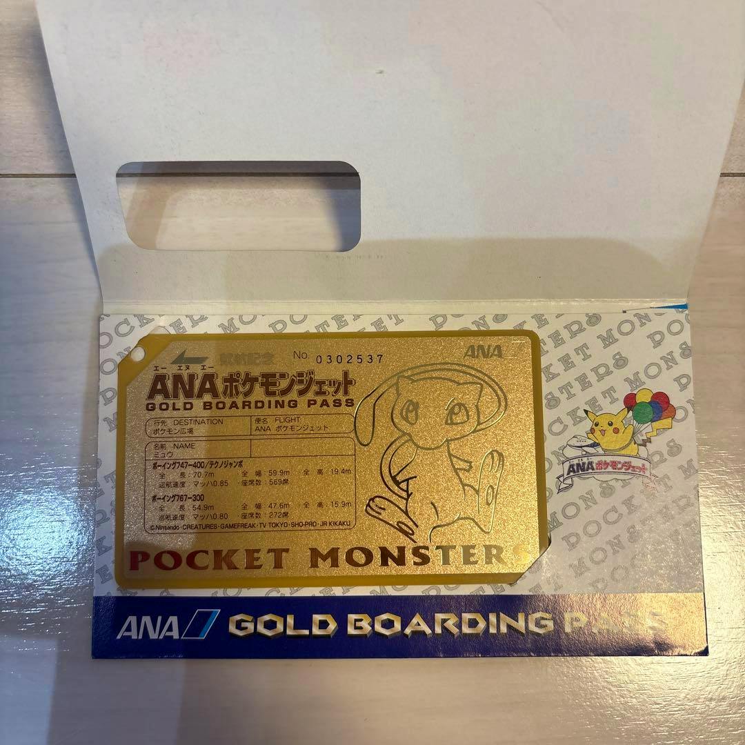 A gold ANA Pokémon gold boarding pass card showing a printed Mew illustration and text inside its paper sleeve.