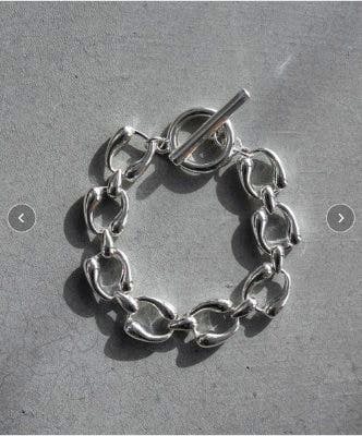 Anchor chain bracelet with toggle clasp laid flat on a grey surface.