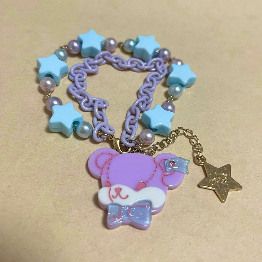 Pastel purple bracelet with blue star beads, pearl-like beads, and a pink-lavender bear-face charm with a gold star dangle.
