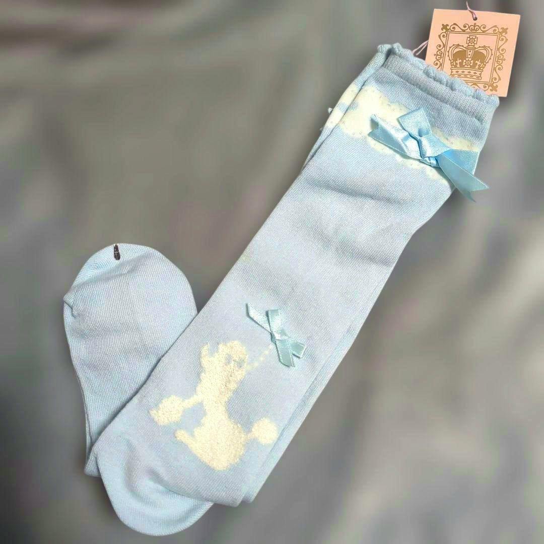 Light blue women's socks (cotton) laid flat showing a white poodle pattern, small satin bows, and a hang tag on a gray background.