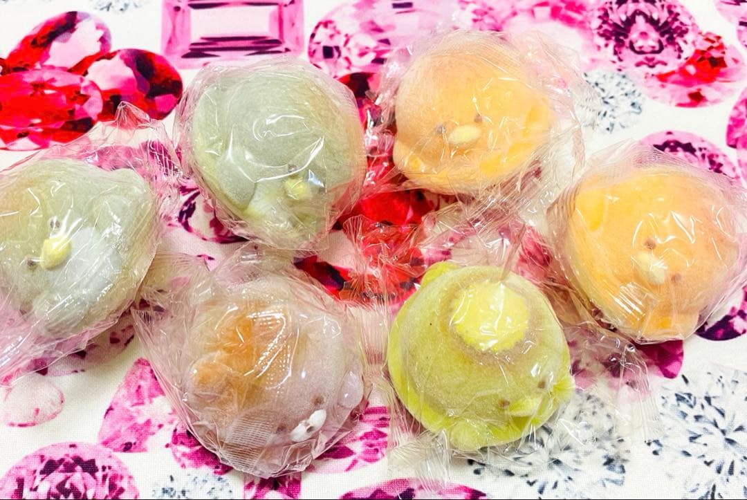 Six small animal-shaped figures wrapped in plastic are arranged on a patterned surface.