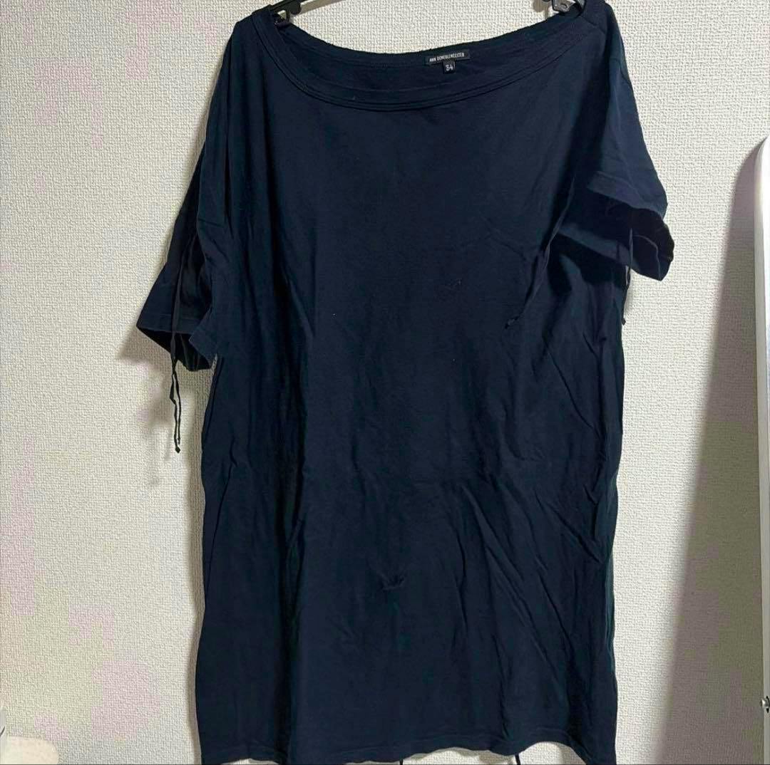 Black ann demeulemeester T-shirt (size 34) hanging on a hanger against a textured wall.