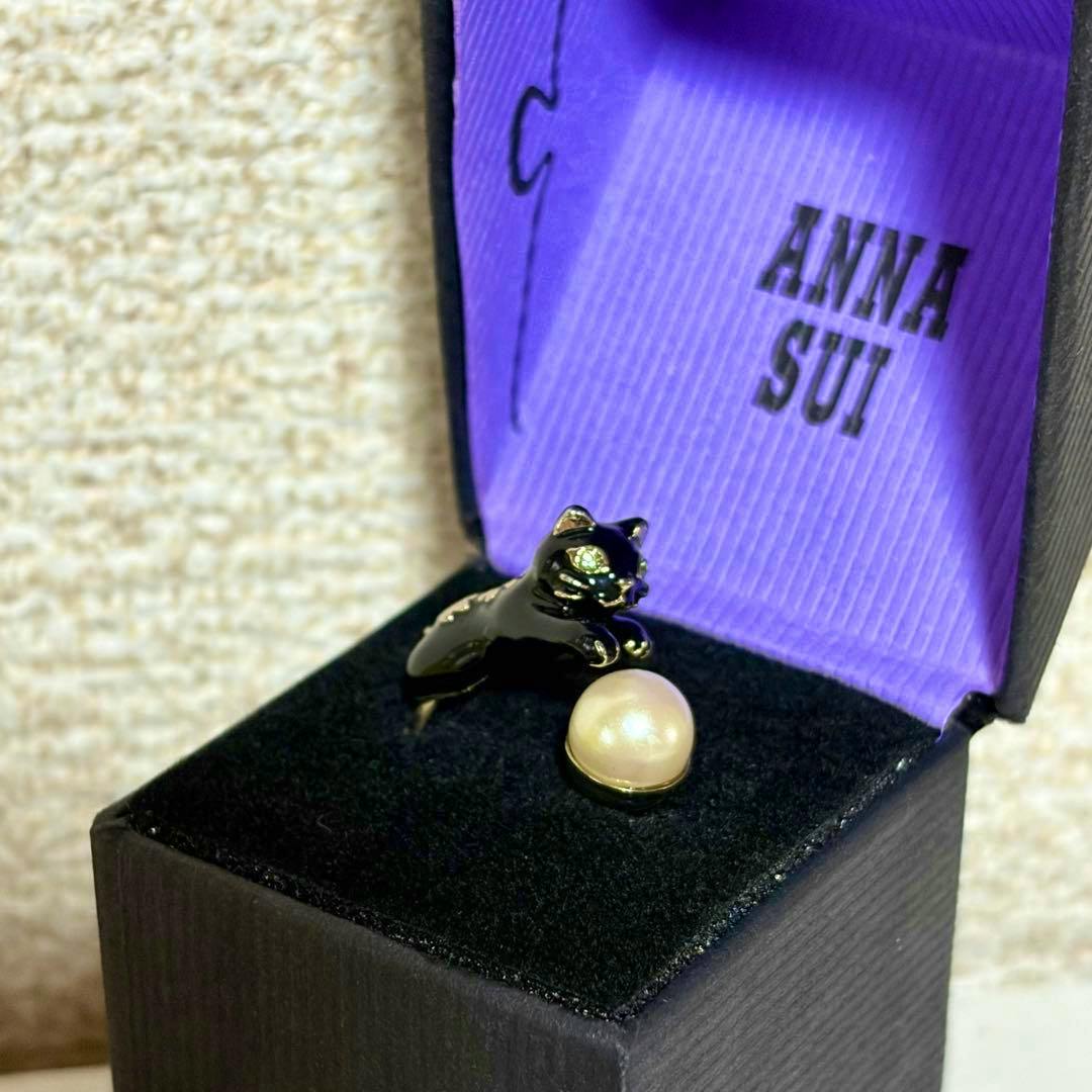 Black cat pearl ANNA SUI ring displayed in an open black box with purple lining.