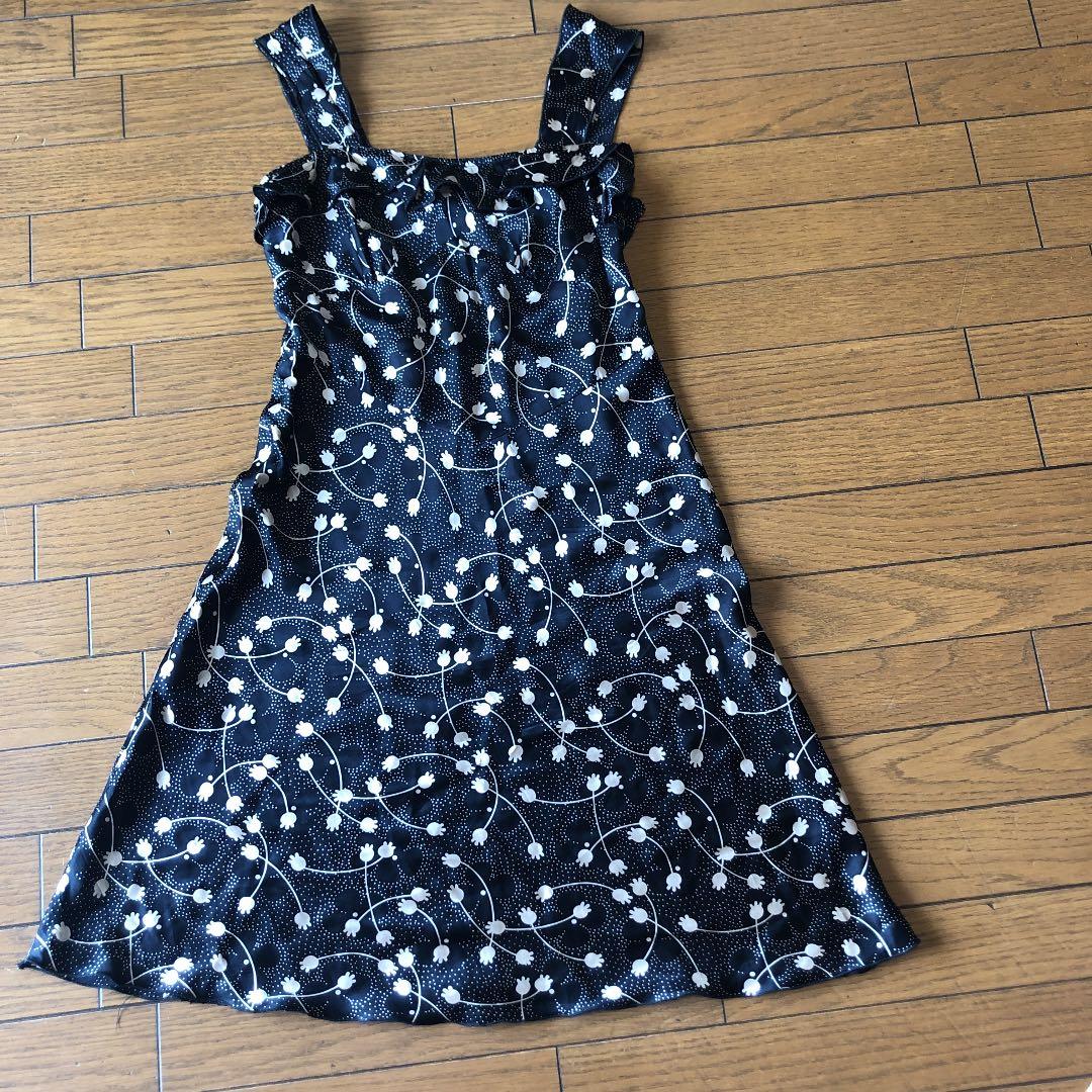 Black ANNA SUI silk dress (size 4/M) with a white floral pattern laid flat on a wooden floor.
