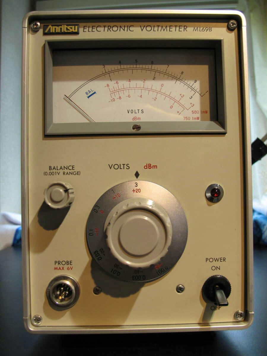 Front view of an Anritsu ML69B electronic voltmeter showing the analog meter, large range knob, probe connector, balance control, and power switch.