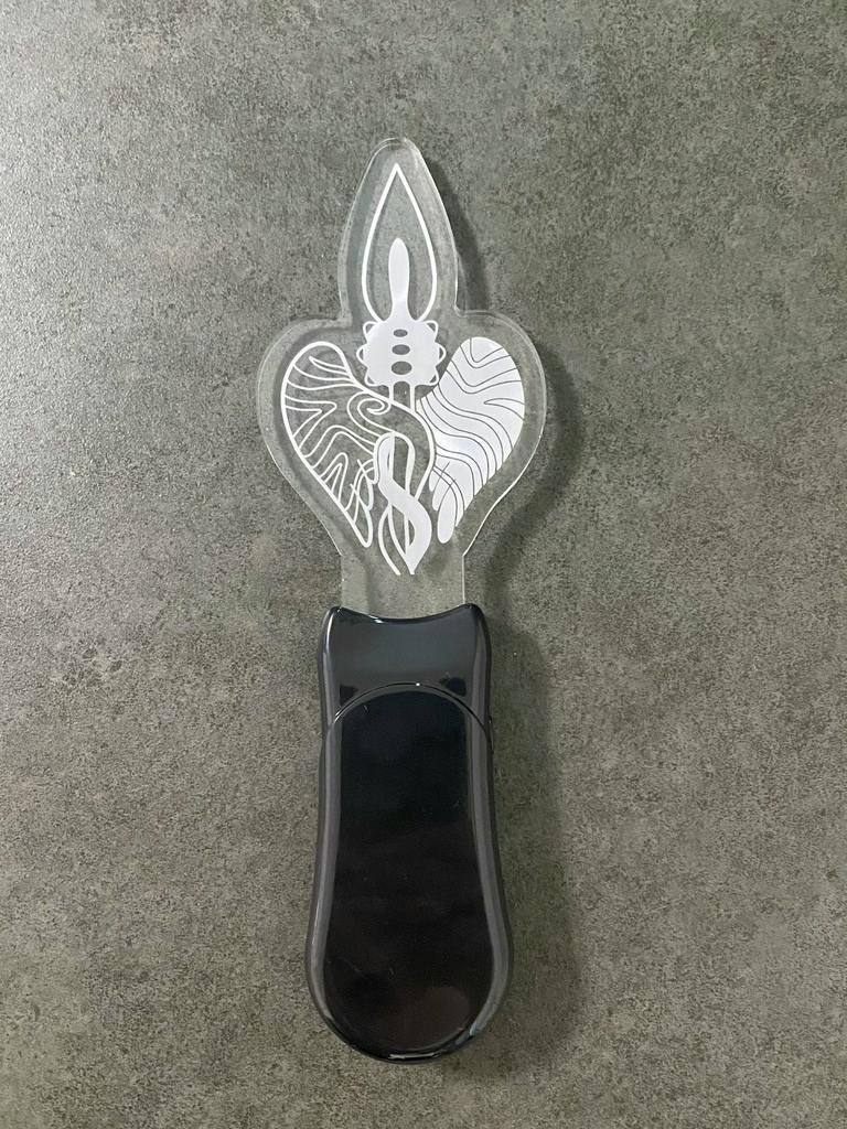 A black-handled acrylic pen light with a heart-shaped acrylic top showing a candle design, photographed on a gray surface.