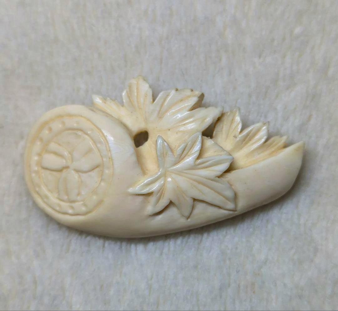 Close-up of a carved tusk obidome showing maple-leaf decorations and a circular crest-like carving.