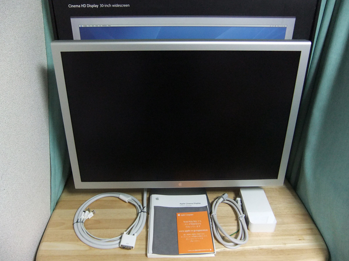 Front view of an Apple 30-inch Cinema HD Display monitor with included cables, power adapter, and manuals visible on a table.