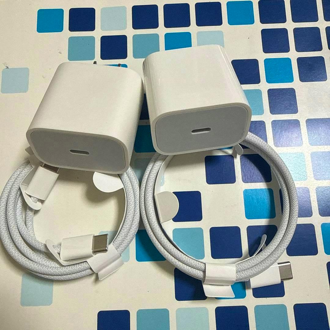 Two white Apple USB-C power adapters with two white USB-C cables on a blue square patterned surface.