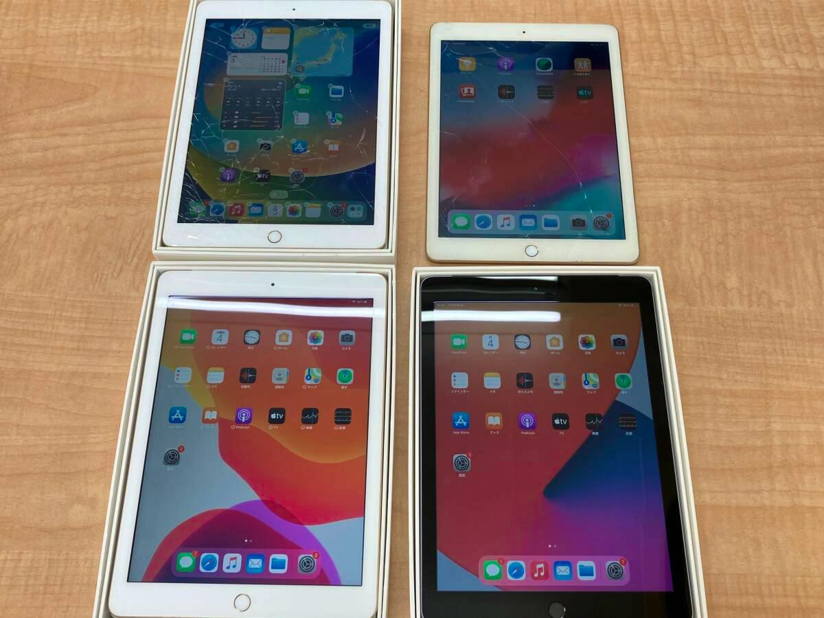 Four iPad (5th generation) tablets placed on a table, with two units showing visible cracked screens.
