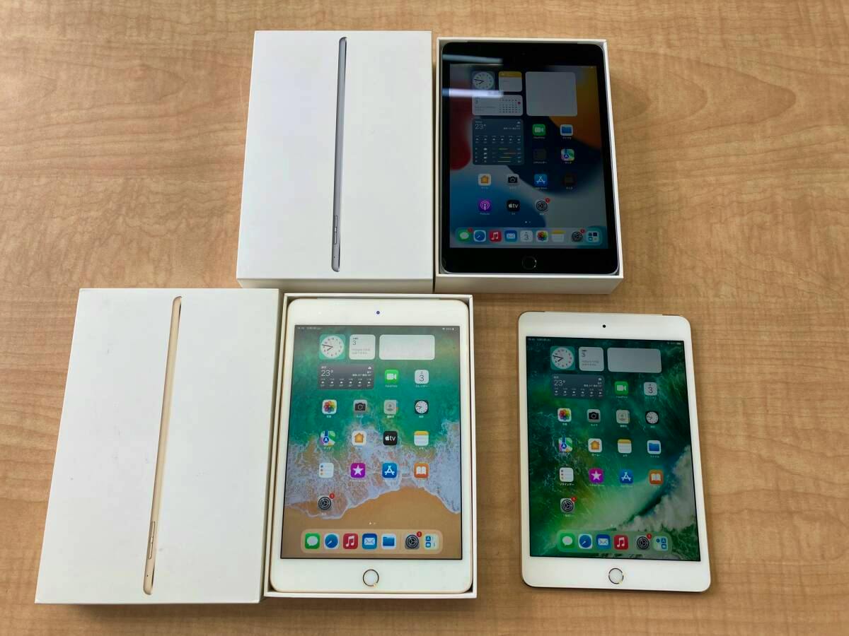 Three iPad mini4 tablets with two iPad boxes displayed on a wooden surface.