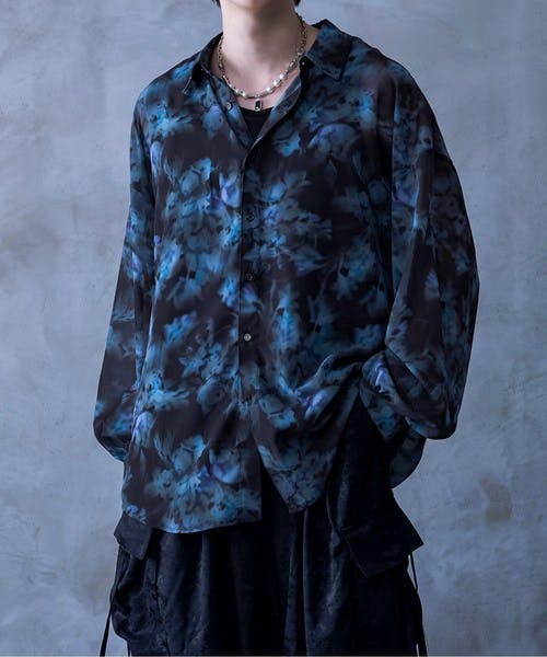A model wearing a dark blue floral-pattern sheer button-up shirt.