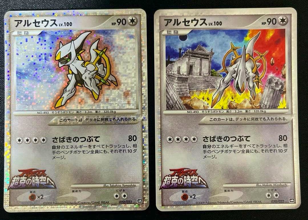 Two Arceus LV.100 Pokémon trading cards placed side-by-side on a dark surface, showing the card artwork and Japanese text.