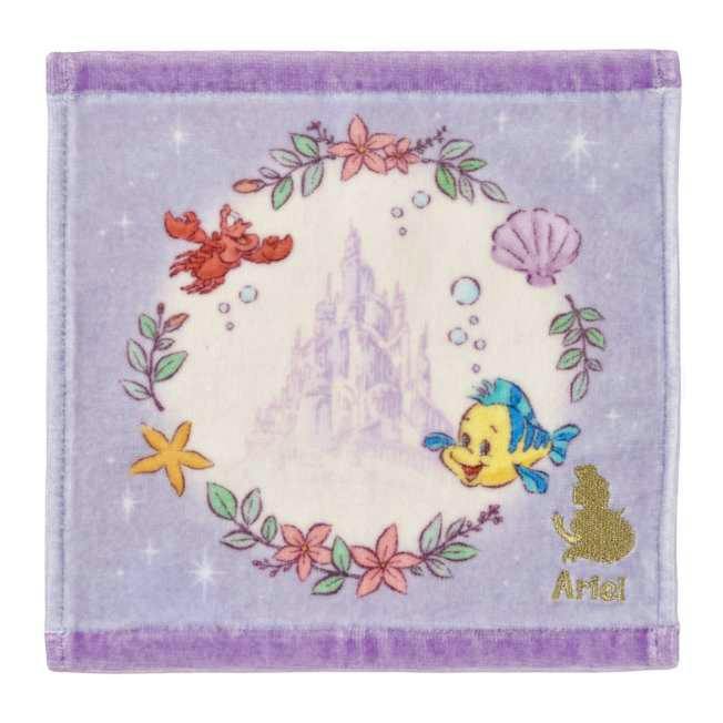 Square lavender mini handkerchief showing a faint central castle motif surrounded by floral wreath, Flounder and Sebastian illustrations, a shell and a gold Ariel silhouette.