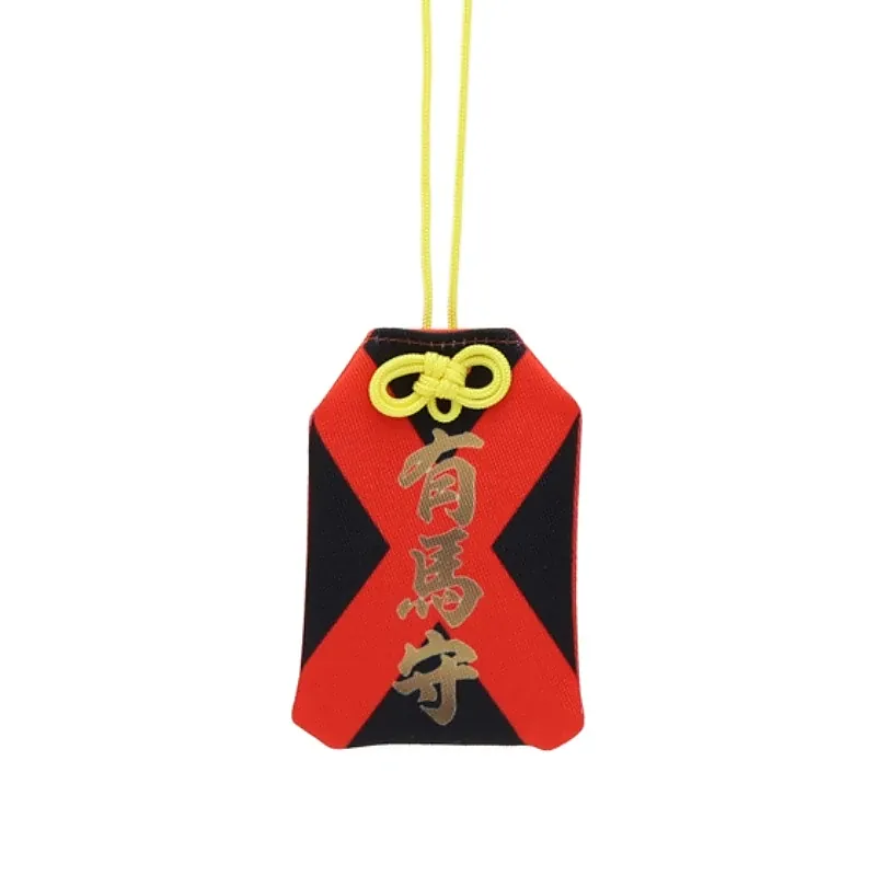 Front of a red and black cloth amulet with gold Japanese characters and a yellow cord.