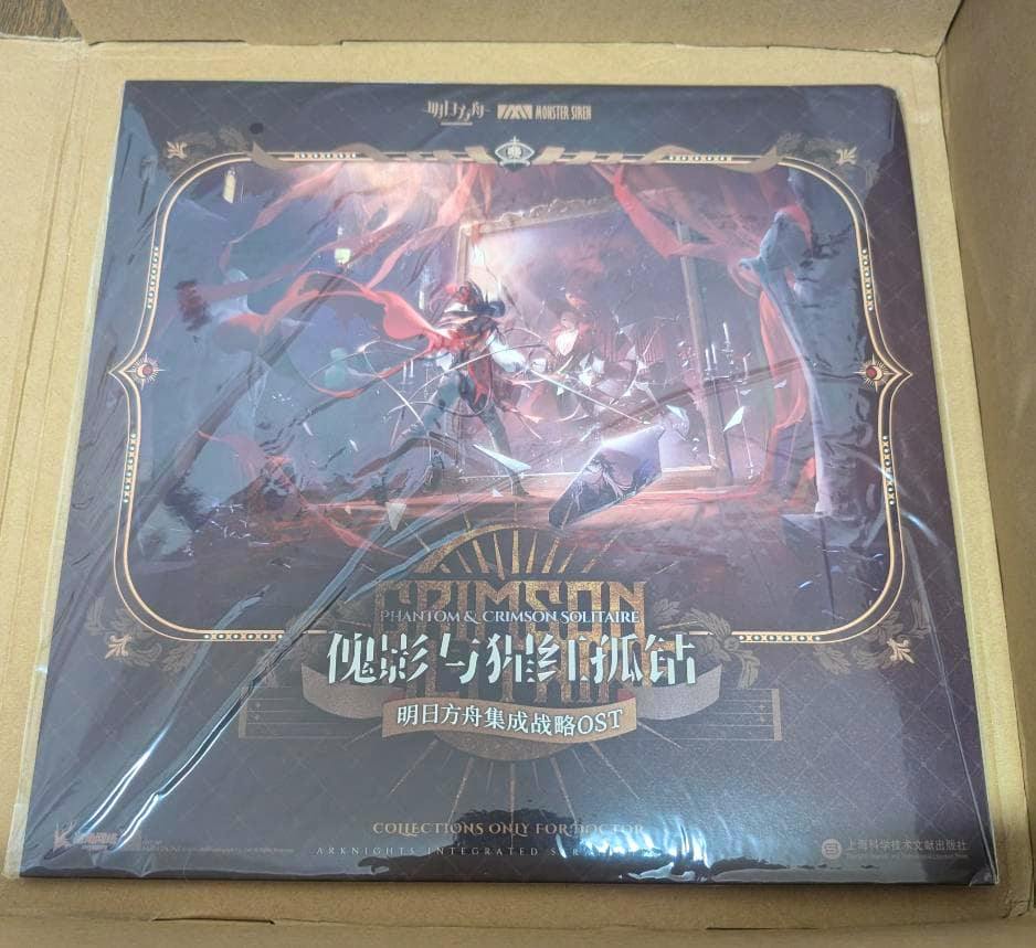 Sealed vinyl record set in shrinkwrap showing the illustrated 'Phantom & Crimson Solitaire' cover placed inside a cardboard box.