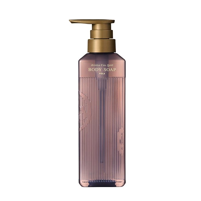 A tall translucent pump bottle of body soap with vertical ribbed sides and a gold pump.