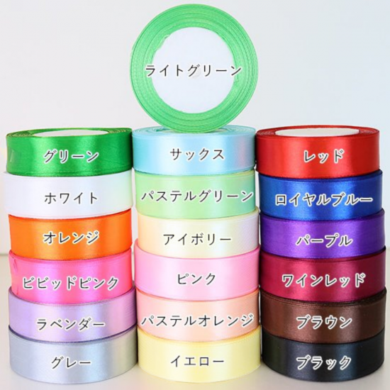 Stacked rolls of satin ribbon in various colors labeled with Japanese color names.