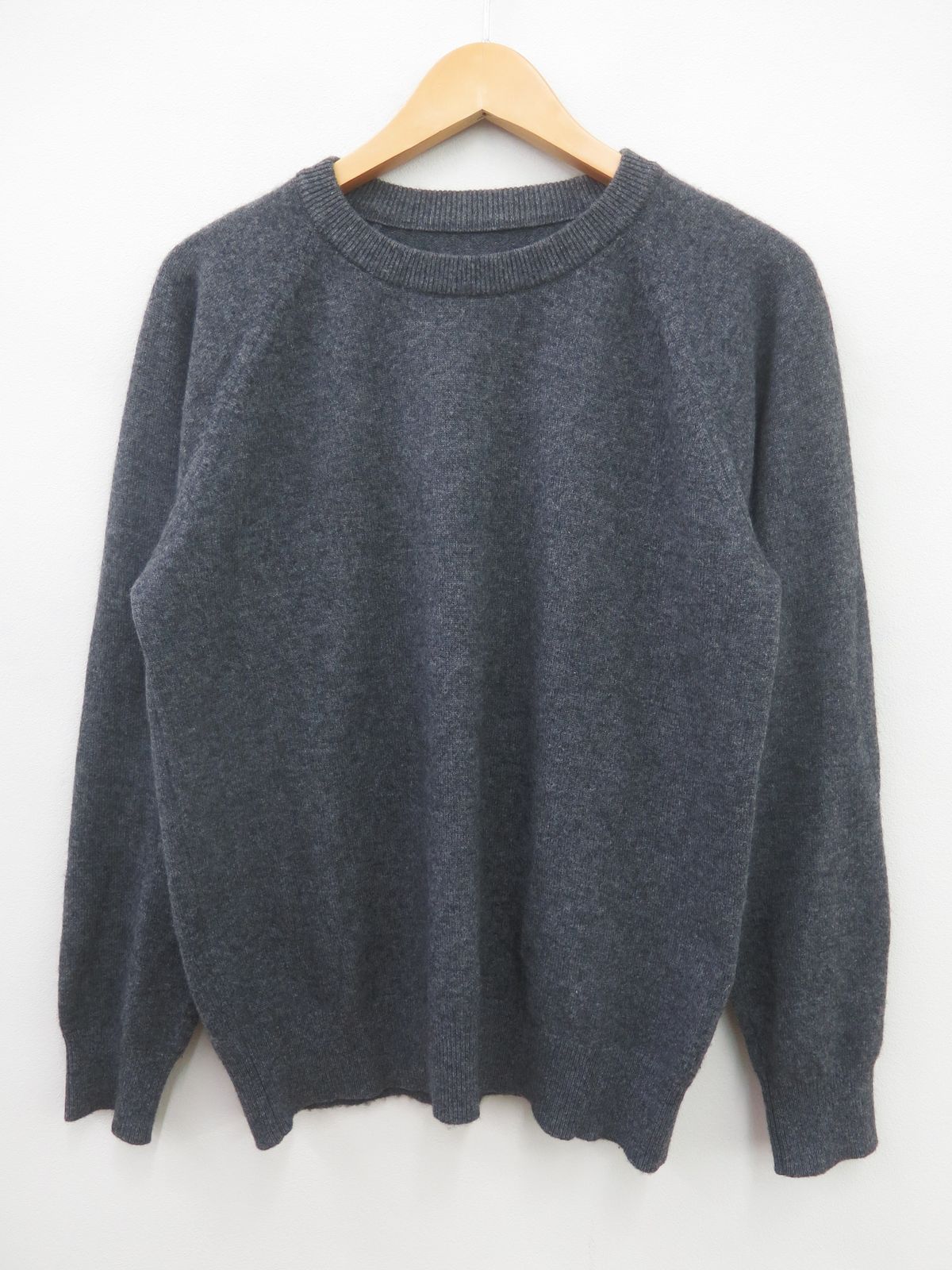 Dark gray cashmere sweater on a hanger against a white background.