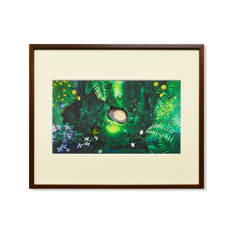 Framed art print showing Totoro lying in a green forest scene with ferns and flowers.