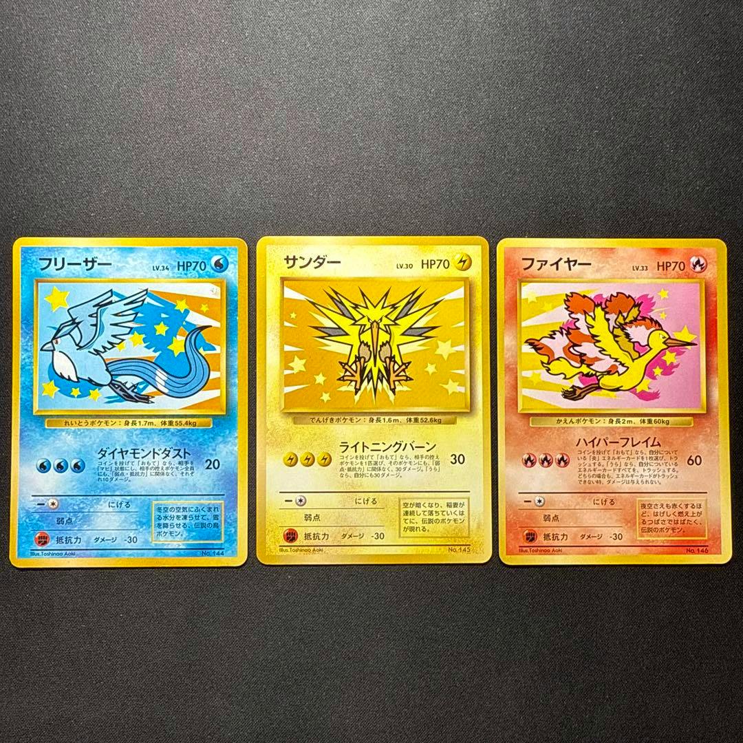 Three Japanese Pokémon promo trading cards (フリーザー / サンダー / ファイヤー) laid side by side on a dark background.