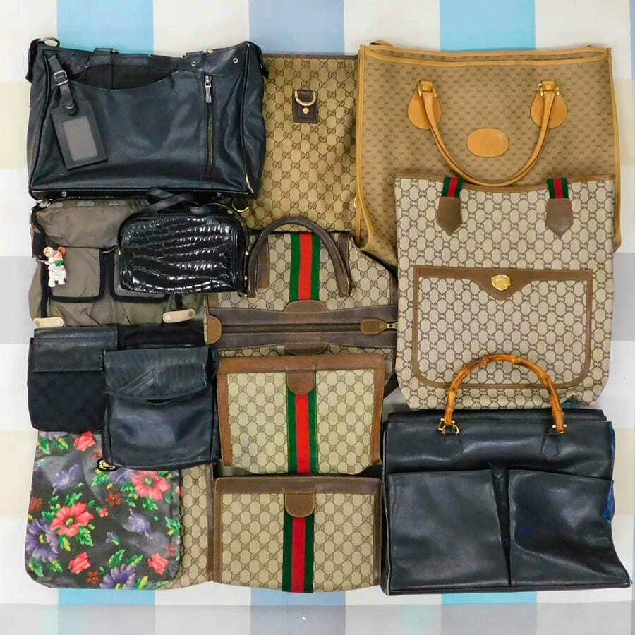 Flat lay of multiple bags arranged in a grid, including several Gucci monogram canvas totes, black leather bags, and a floral pouch.