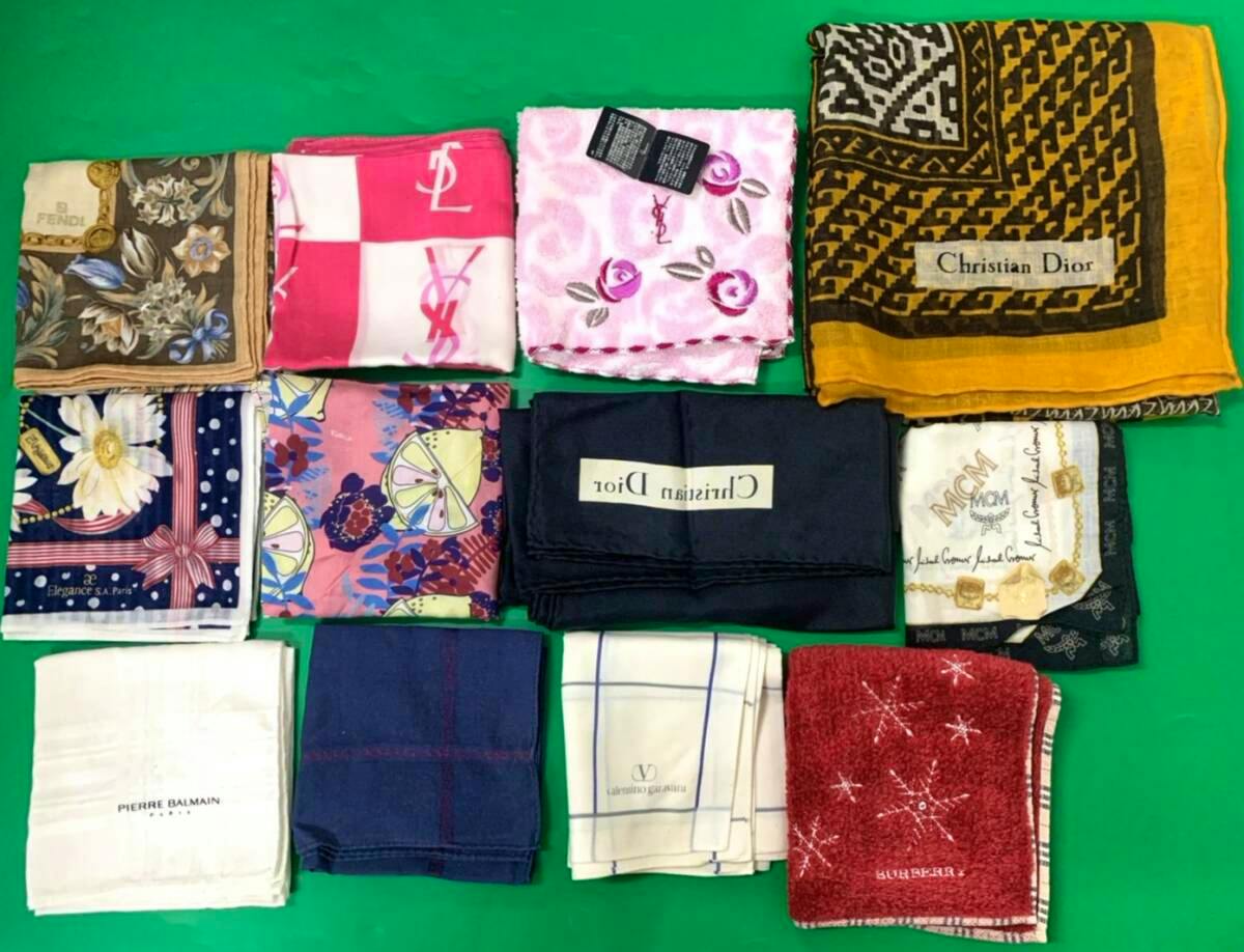 Twelve folded branded scarves, handkerchiefs, and towels arranged on a green background with a visible Christian Dior label.