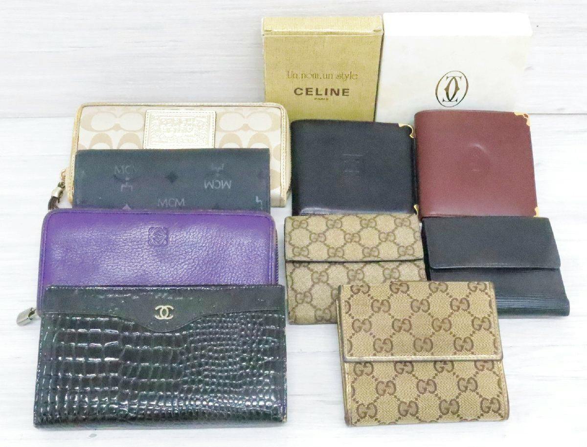 Several assorted wallets in different colors and patterns displayed on a light surface with boxes behind them.