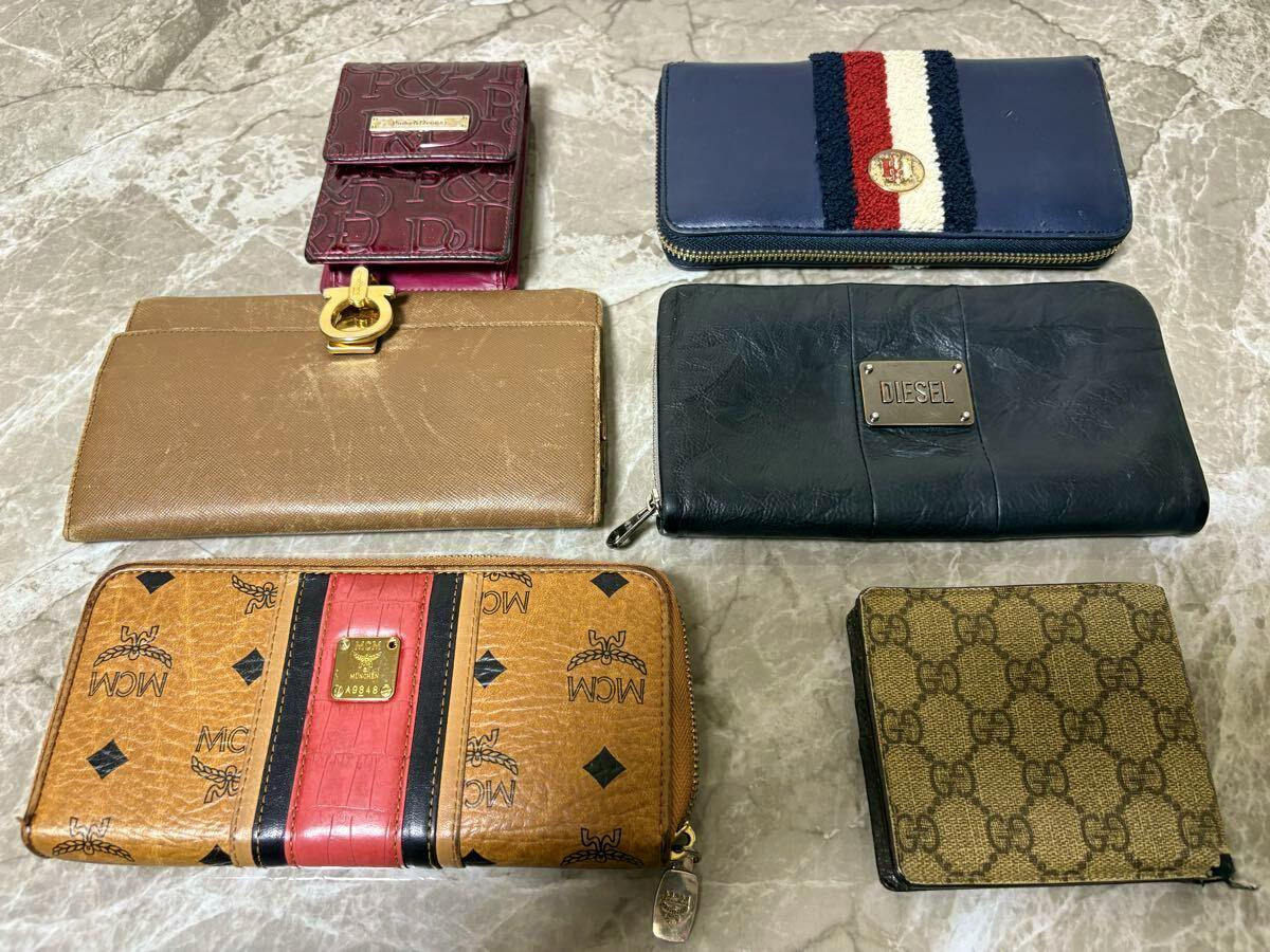 Several branded wallets arranged on a marble surface, including a Gucci monogram wallet at the lower right.