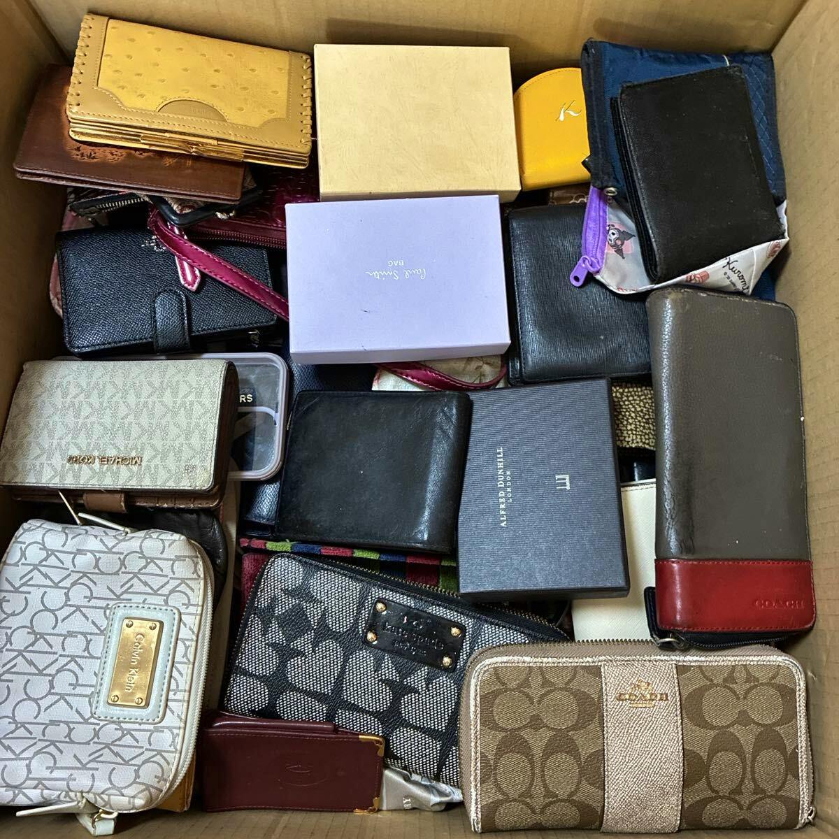 Cardboard box filled with assorted branded wallets and small purses stacked together.