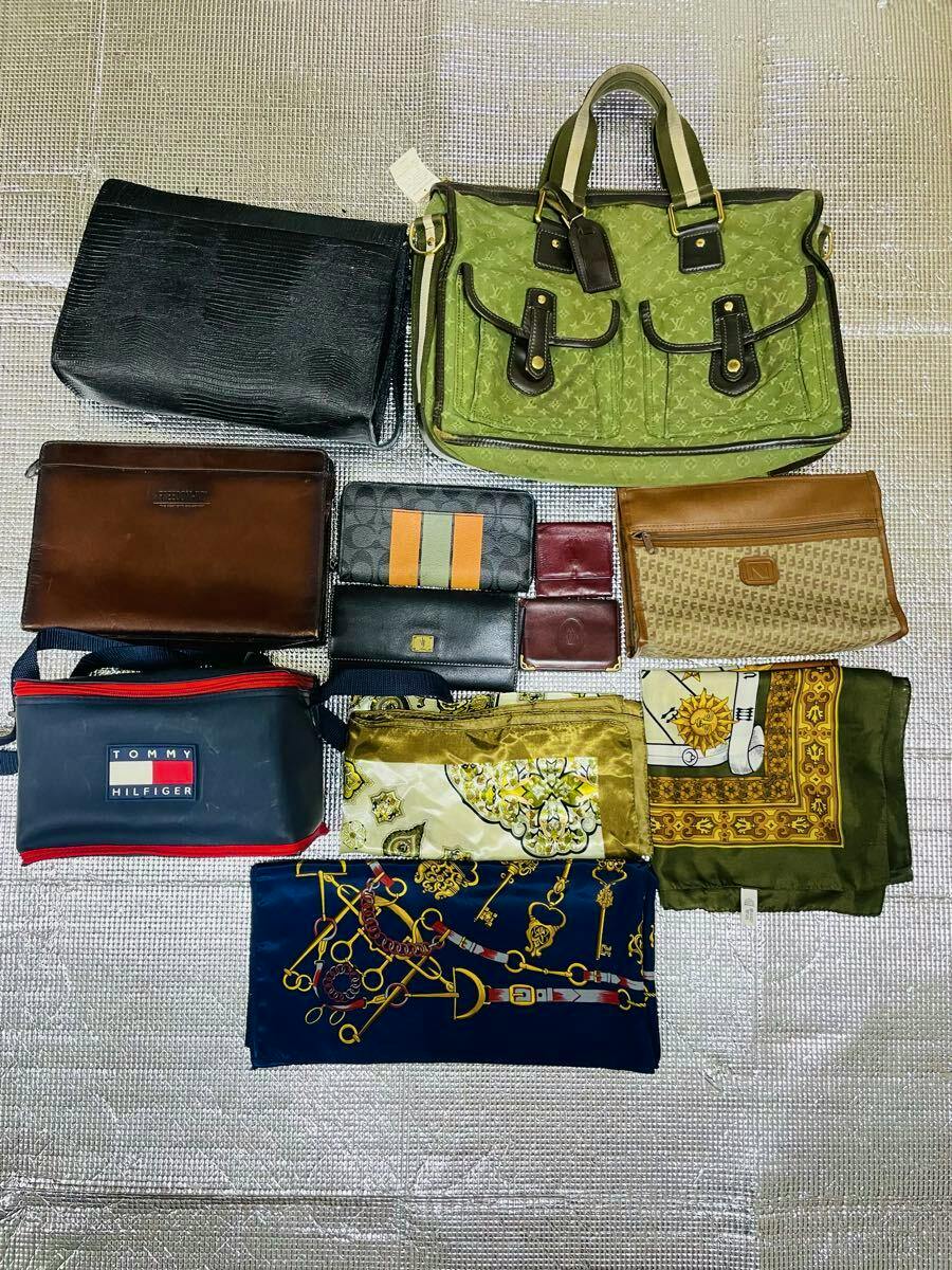 A laid-out assortment of 11 items — bags, wallets, pouches, and scarves — including a green monogram tote at top right.